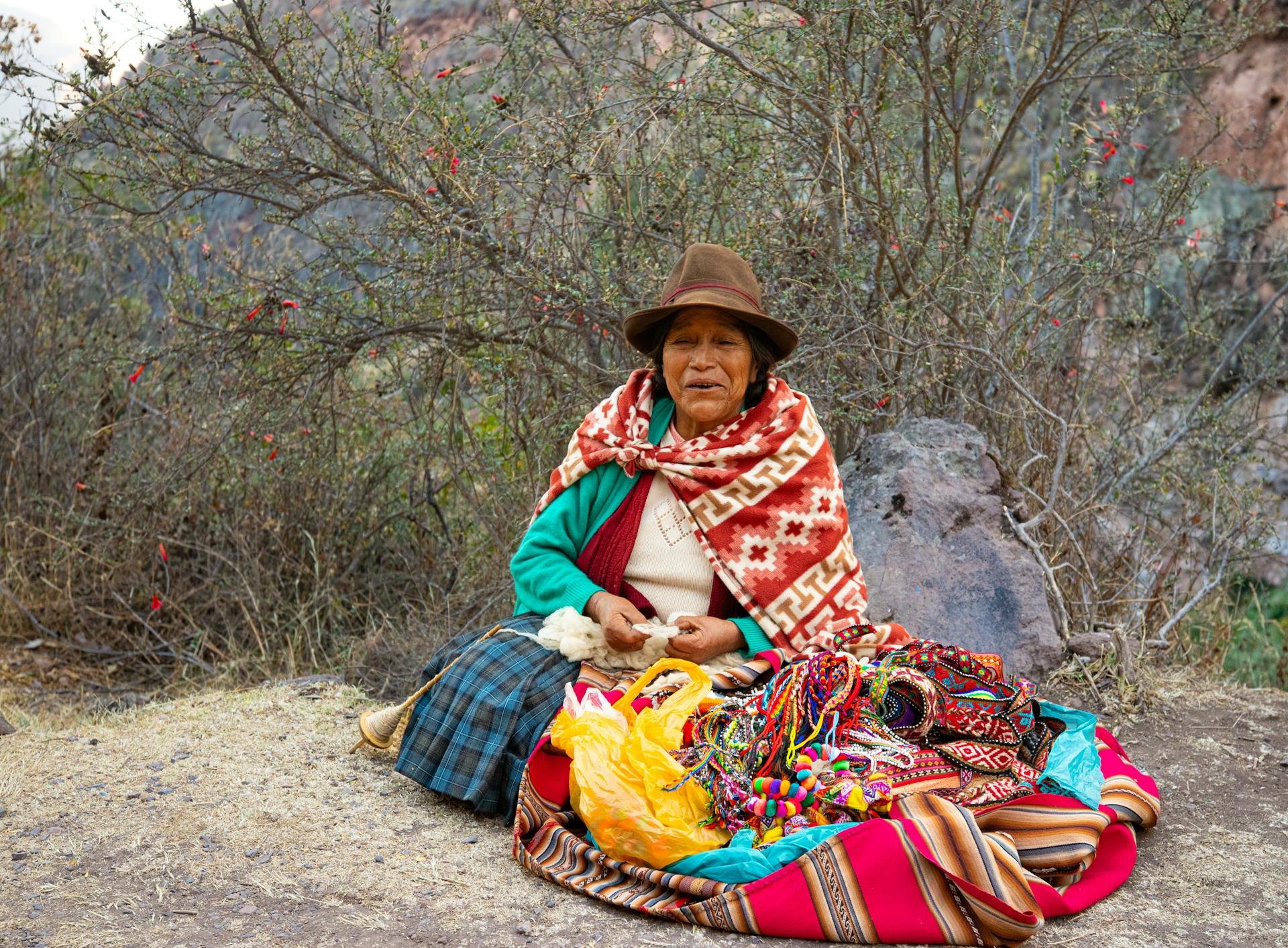 Elderly Woman with Hat and Scarf Sitting on Trail by Bush