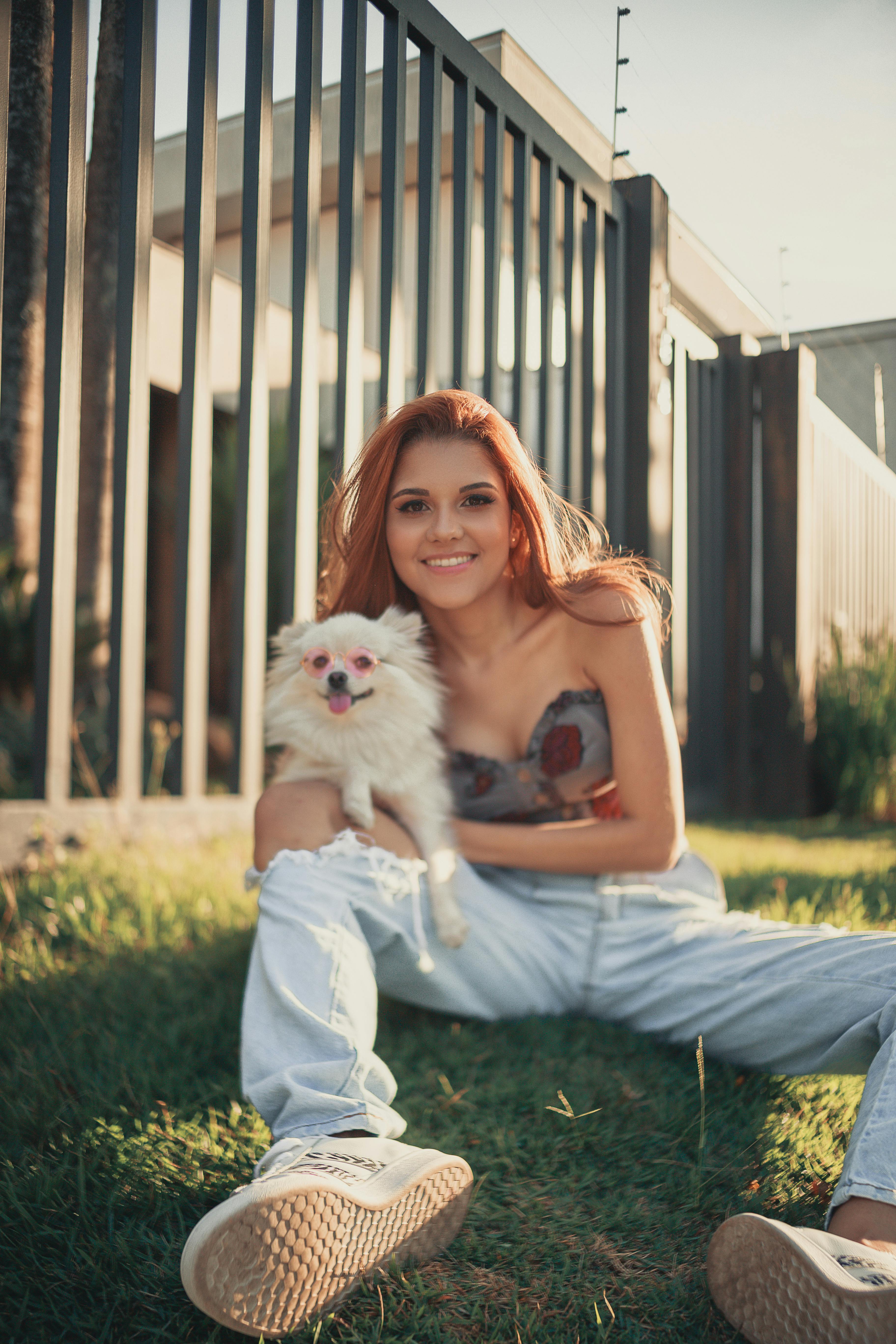 smiling woman sitting with dog on grass