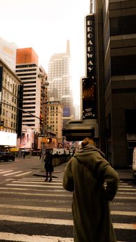 A woman crosses a bustling Broadway street in NYC, capturing the urban essence.