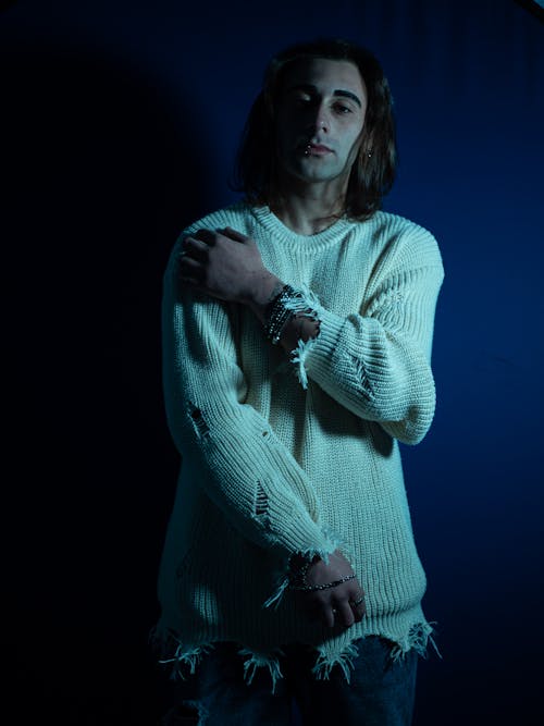 A man in a sweater and jeans poses for a portrait