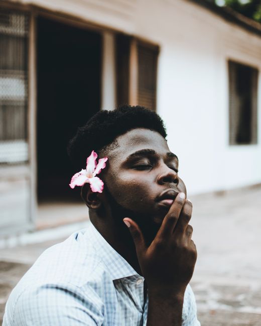 Close-up portrait of a man with a flower behind his ear, captured outdoors in Malindi, Kenya.