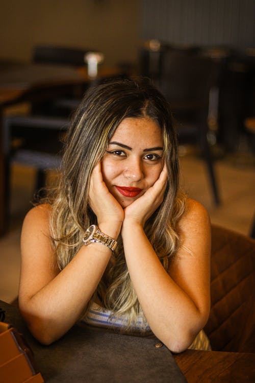 Blonde Woman Sitting with Hands on Cheeks