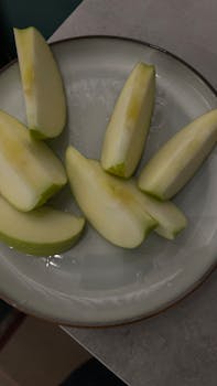Sliced green apples arranged on a white plate for a simple food aesthetic.