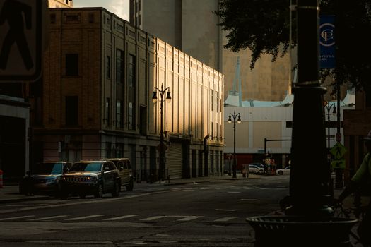 A quiet urban street scene with cars parked, facades sunlit at dusk, creating a warm atmosphere.