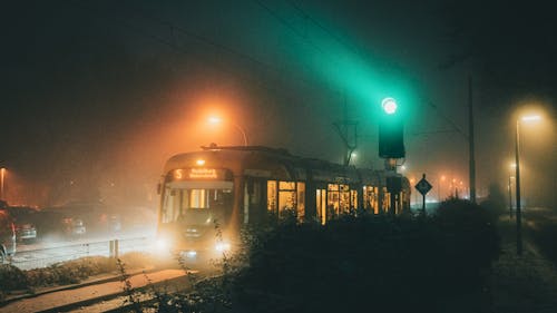 A train on a foggy night with green lights