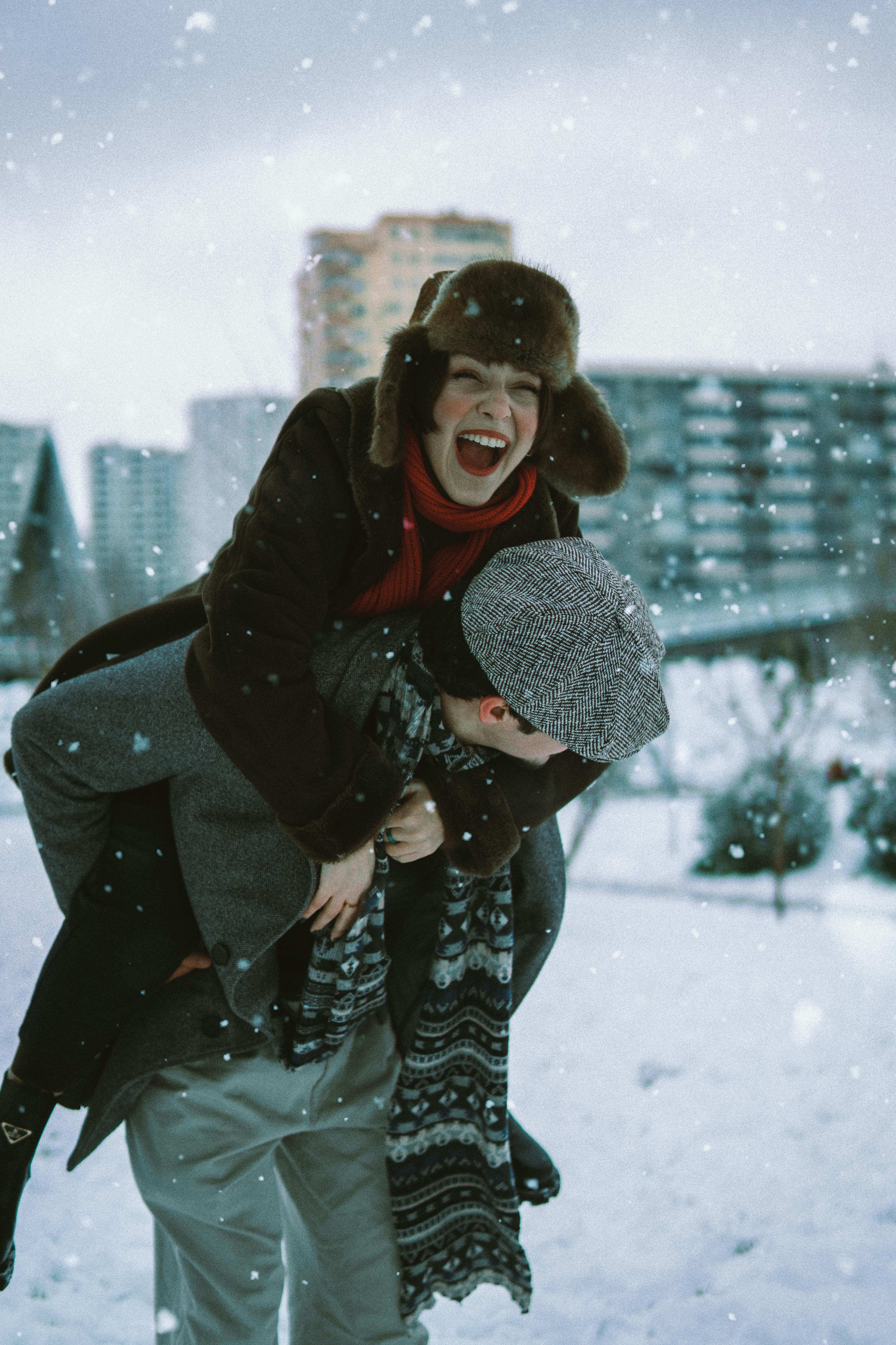 A cheerful couple enjoys a snowy day in Bakü, Azerbaijan, sharing laughter and warmth.