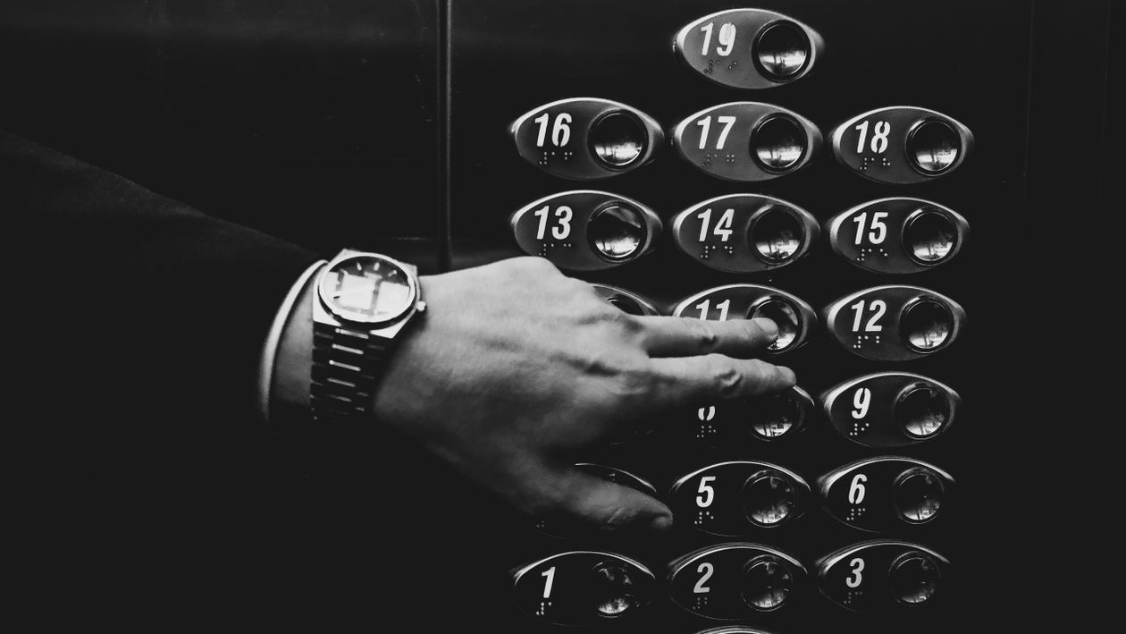 Person pressing a lift control button in an interior