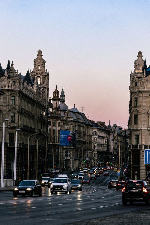 Free A bustling city street at dusk, lined with historic buildings and busy traffic, under a clear sky. Stock Photo