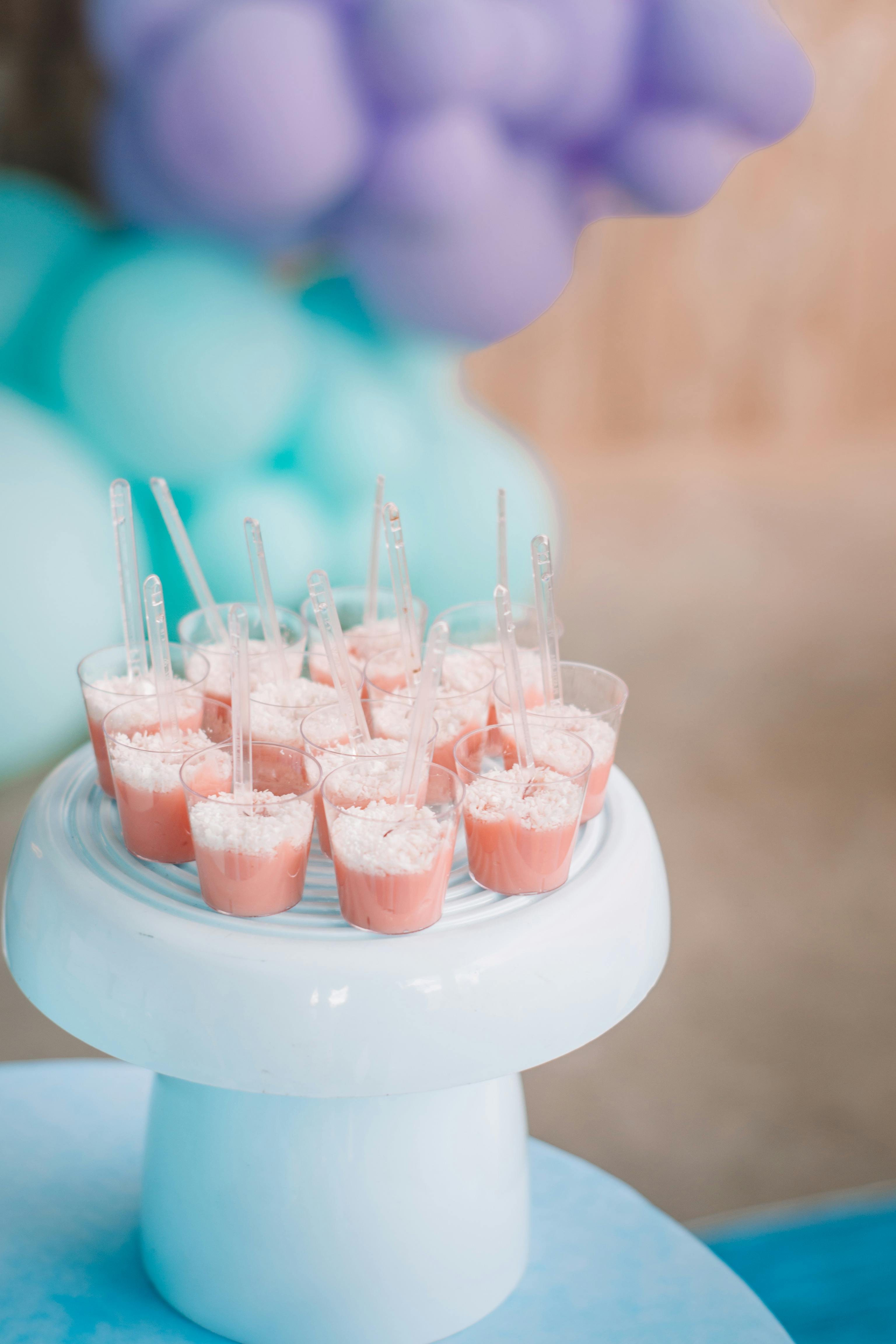 Charming pastel dessert cups with pink ice cream on a blue stand, perfect for events.
