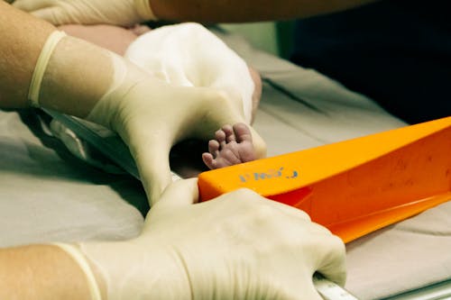 Nurse Hands Holding Newborn Foot