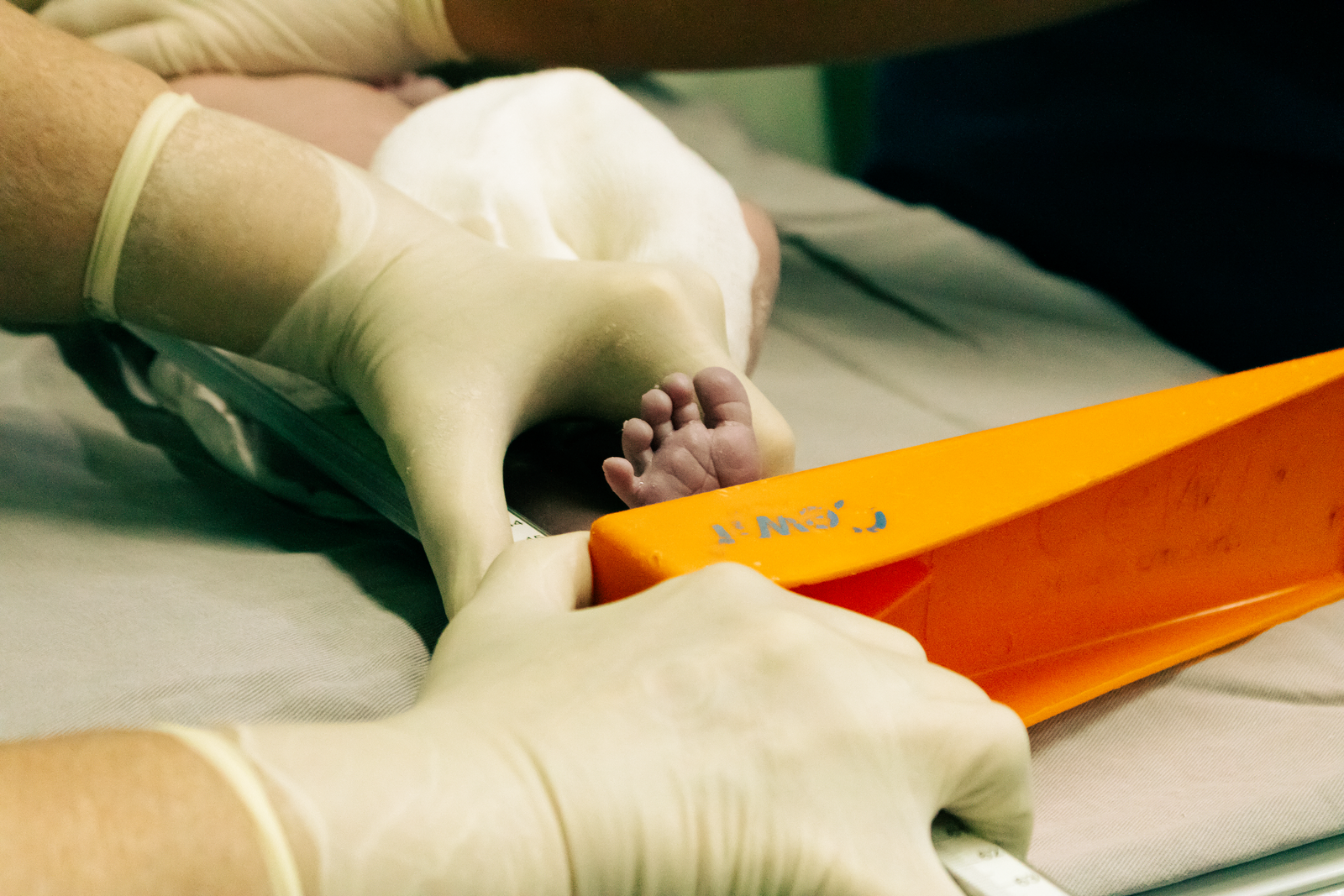 A nurse gently measuring a newborn baby foot
