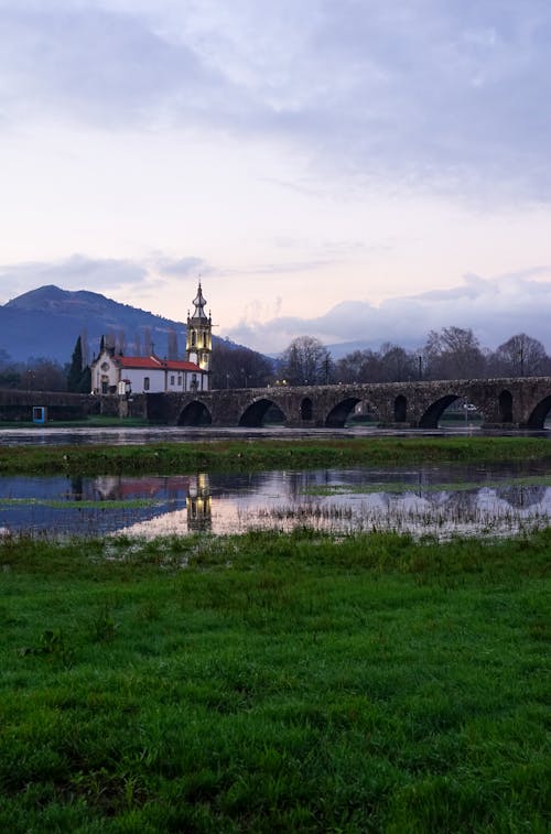 Stone Bridge and Church behind River in Countryside