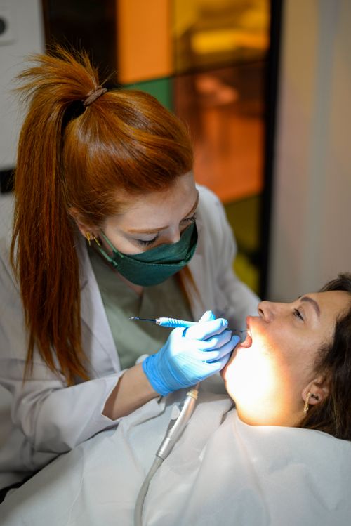 Free A female dentist in a mask and gloves examines a patient indoors under bright light. Stock Photo