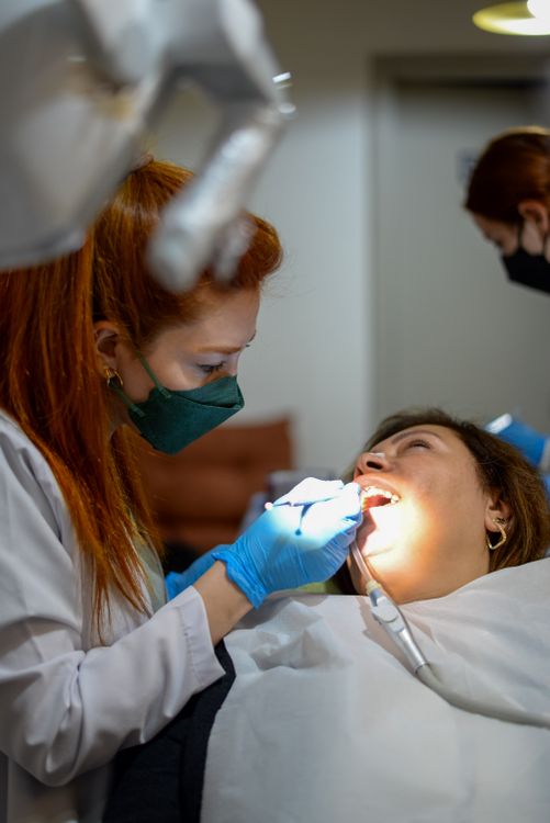Dentist in mask and gloves working carefully on patient in dental chair