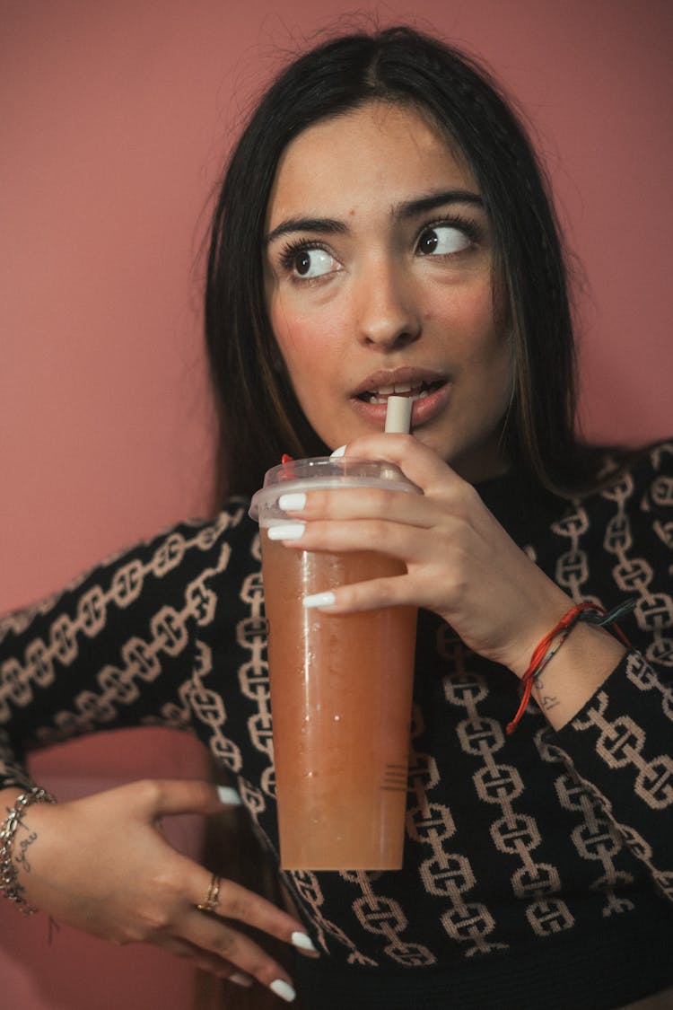 Young Woman Drinking From A Large Cup With A Straw 