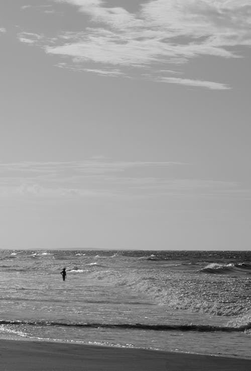 Person Standing on Sea Shore in Black and White