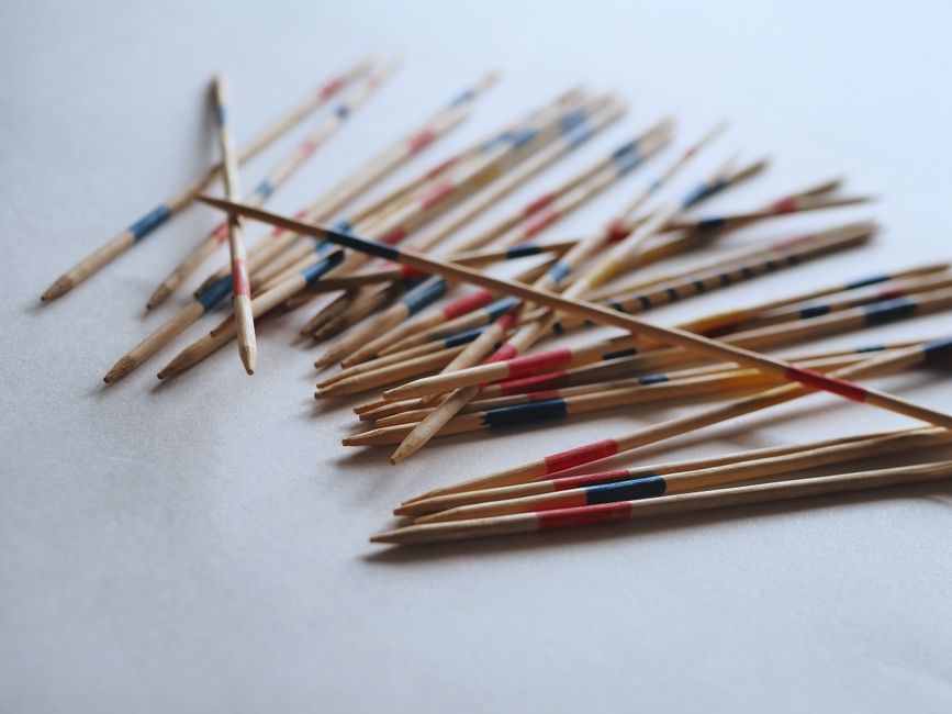 Wooden pick-up sticks with colorful markings spread on white background, emphasizing playfulness.
