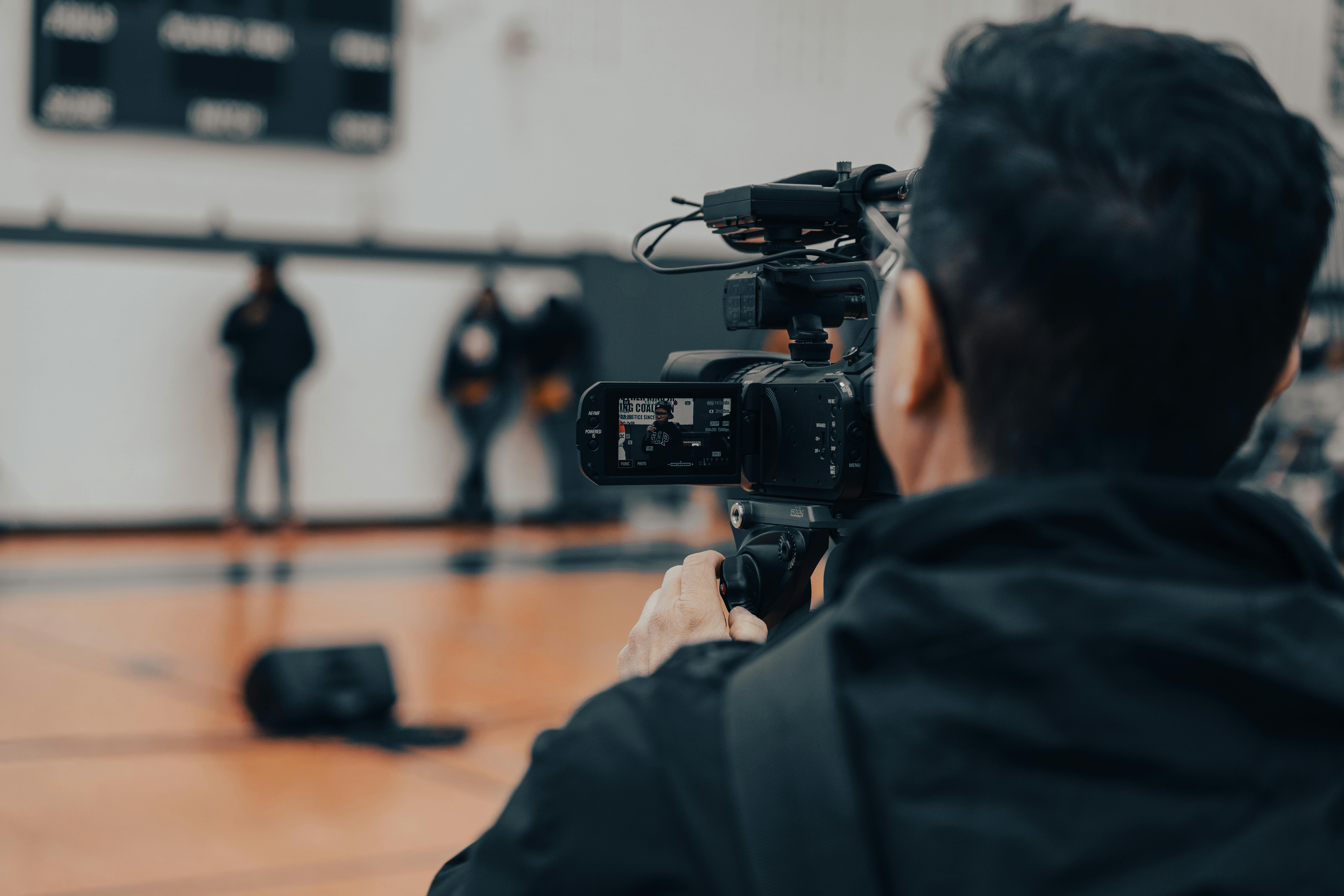 Back view of a cameraman filming an indoor event in Seattle with professional equipment.