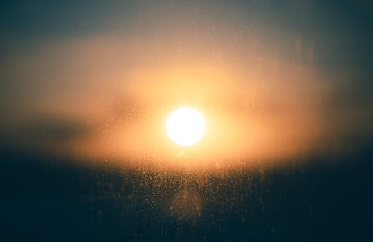Sunset glow through glass with raindrops, creating a tranquil and reflective mood.