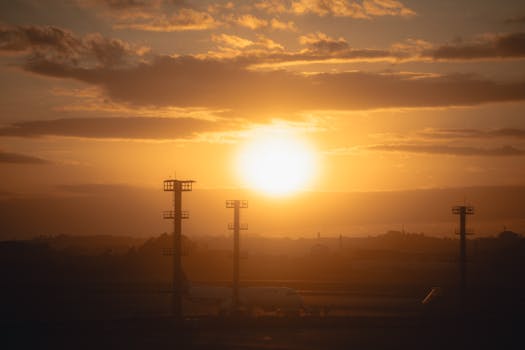 Airplane silhouette against a vibrant sunset skyline at the airport with towering structures.