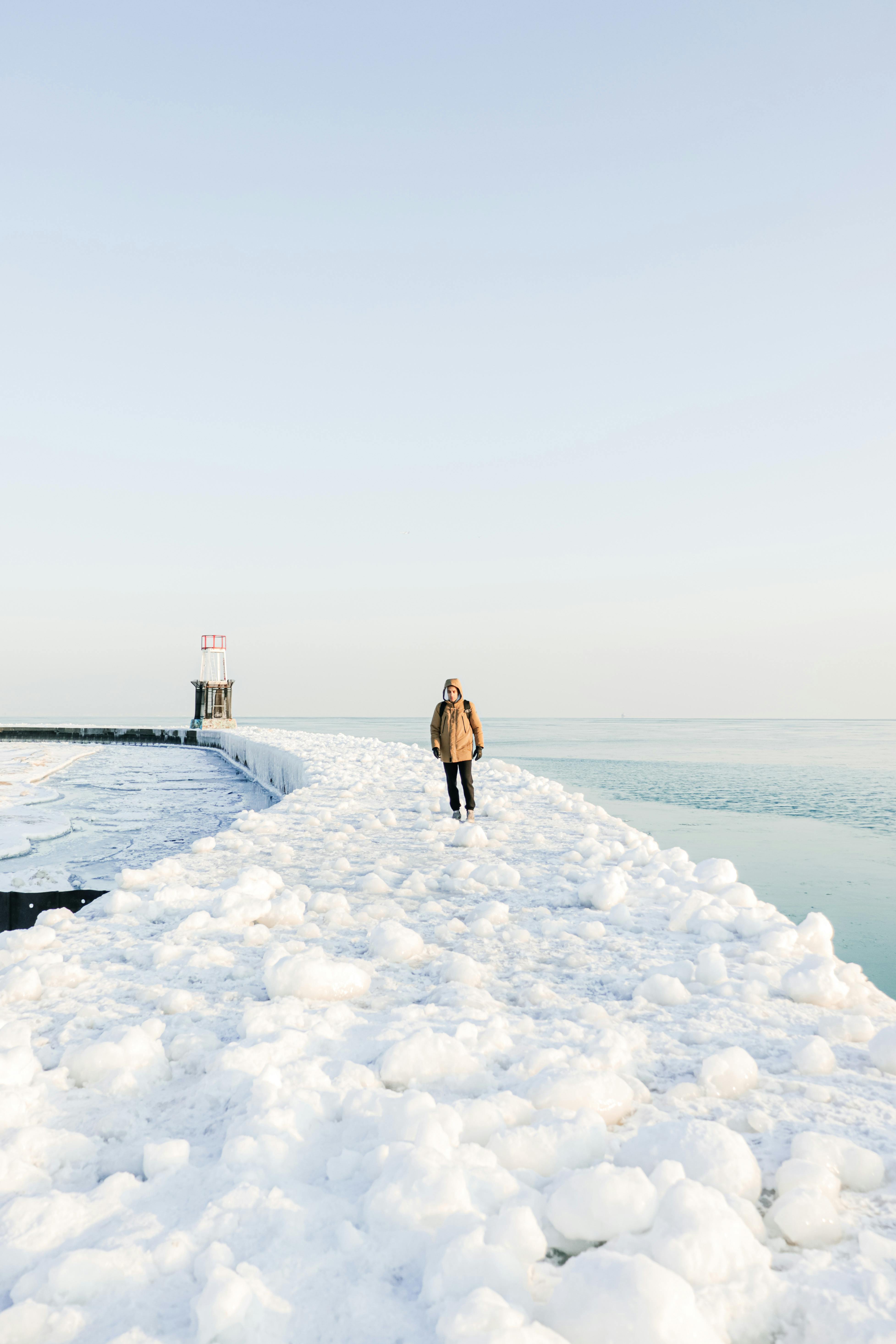 A lone person walks on a snow-covered pier by Lake Michigan in Chicago.
