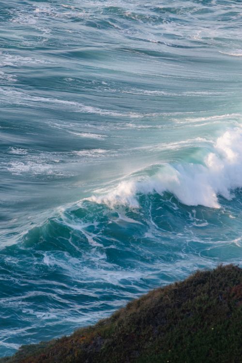 Free Scenic aerial view of turquoise ocean waves crashing against a rocky coastal shoreline. Stock Photo