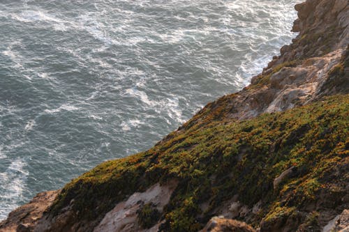 A person standing on a cliff overlooking the ocean