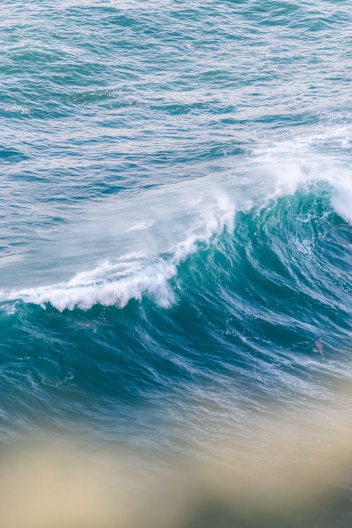 Free Captivating view of a large ocean wave crashing with white foam against the shoreline. Stock Photo
