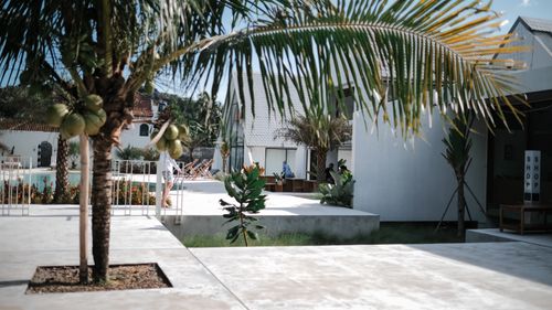 Free A stylish tropical resort featuring palm trees, white buildings, and a pool. Stock Photo