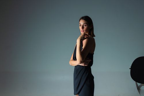 Free Woman in an elegant black dress posing against a gray background. Stock Photo