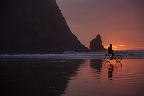 Person on Bike on Beach at Sunset