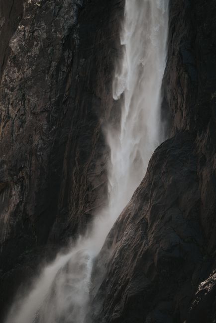 Dramatic view of Yosemite Falls cascading down rocky cliffs in Yosemite Valley, California.