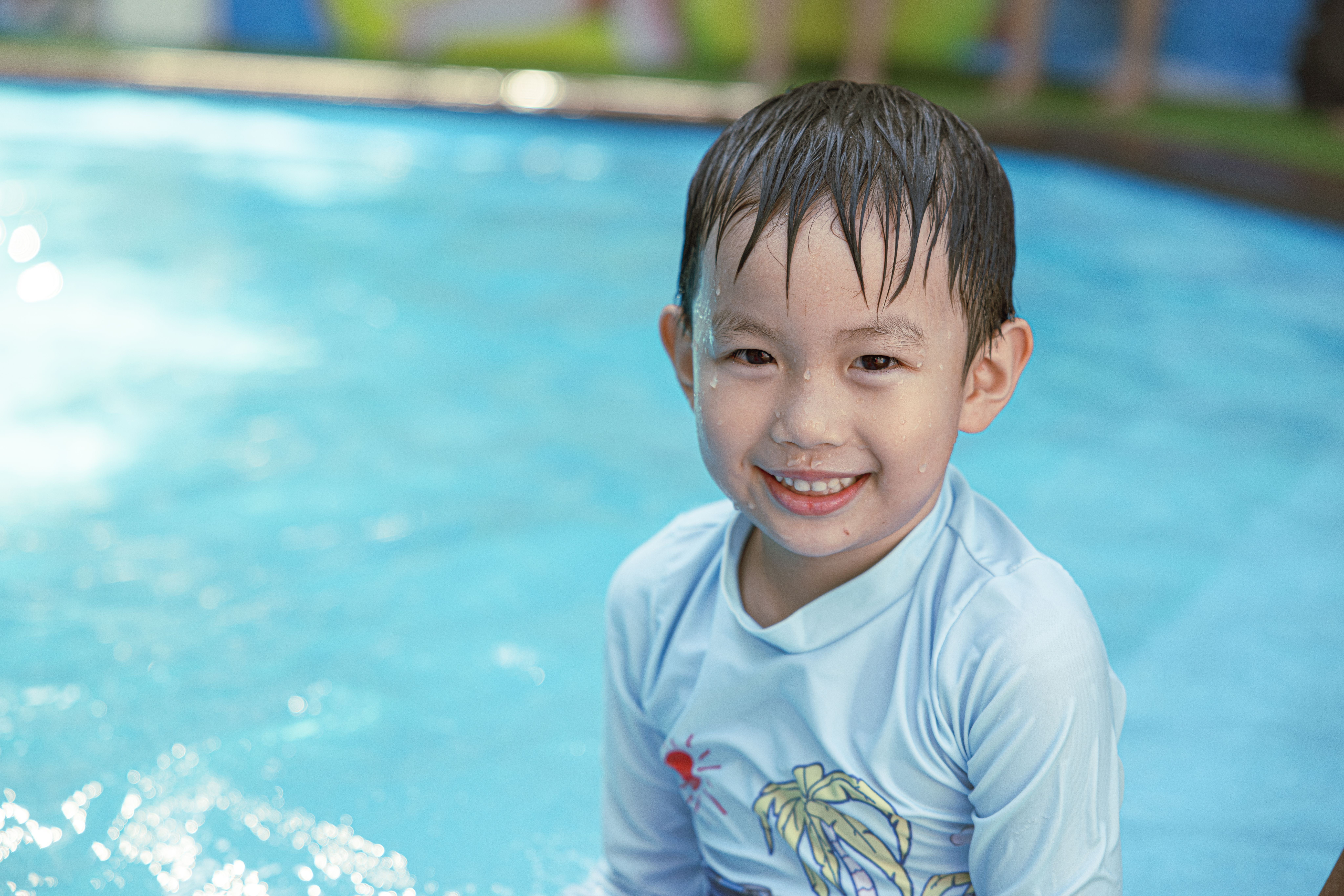 Smiling young boy enjoying a sunny day while swimming in a pool.