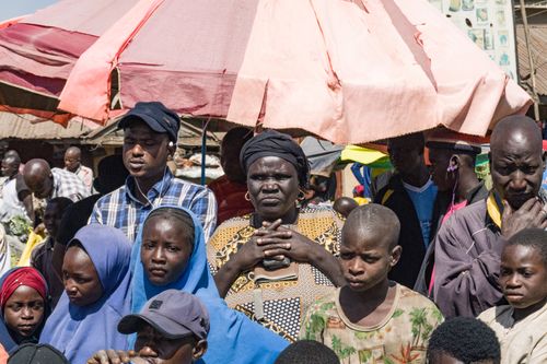 Free Nigerian street market bustling with people under colorful umbrellas. Stock Photo