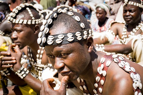 An African dancer looking determined and focused with hand on his chin .