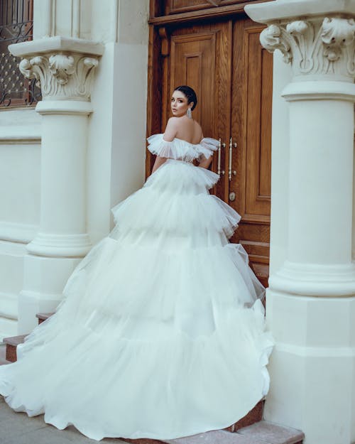 Woman in Wedding Dress Standing Next To Wooden Door