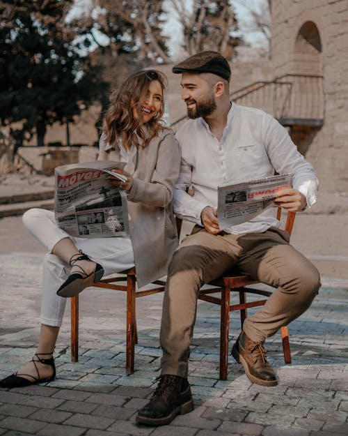 Man and Woman Sitting on Chairs with Newspapers