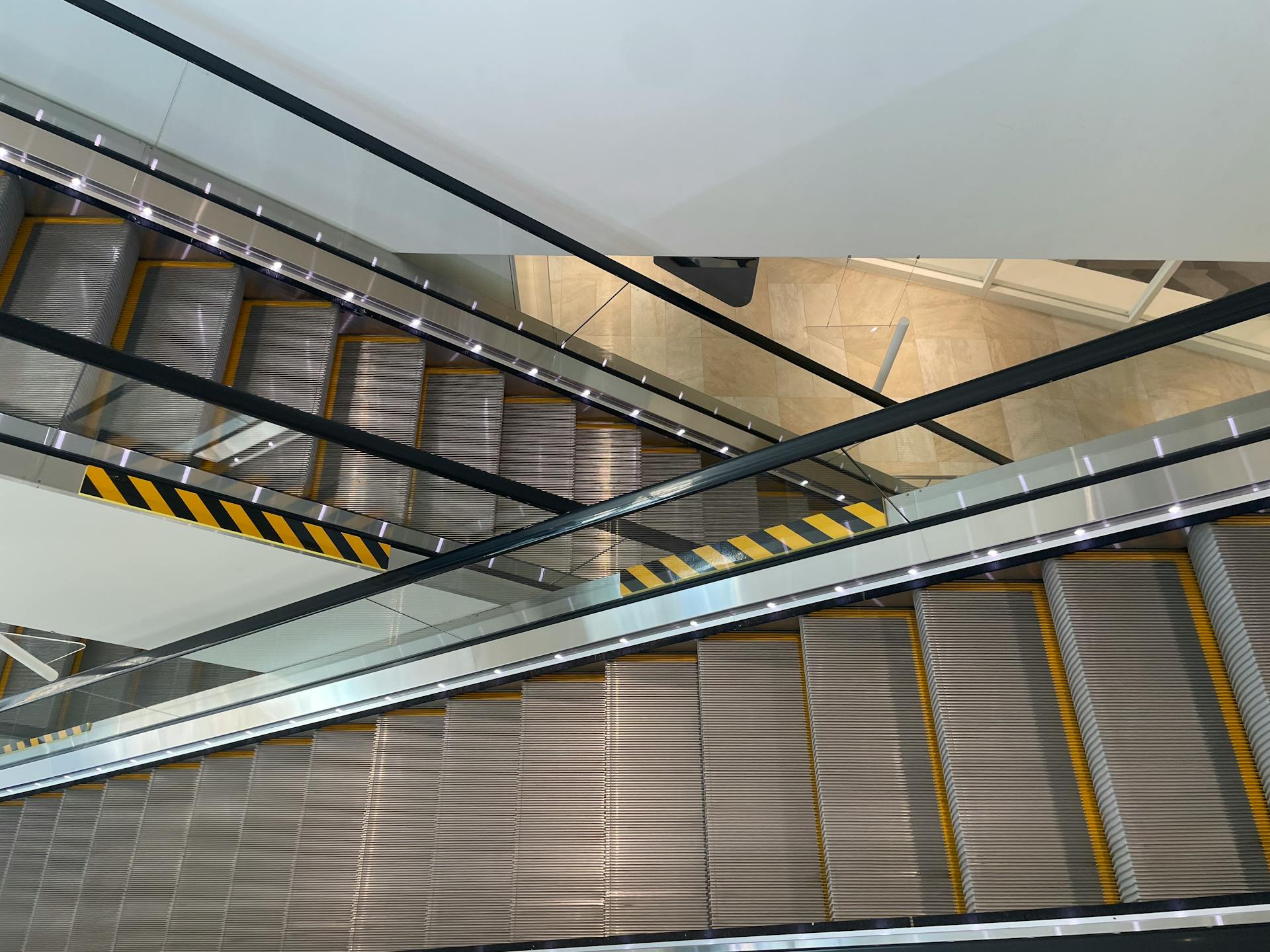 Top-down view of escalators in a shopping mall, highlighting modern architecture and perspective.