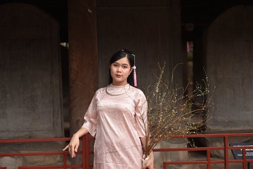 Woman in Traditional Clothing Standing with Plant Branches