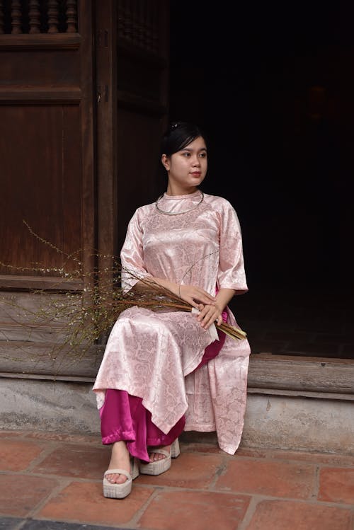 Woman in Traditional Clothing Sitting on Doorstep