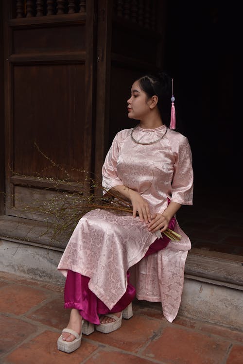 Woman in Traditional Clothing Sitting on Doorstep