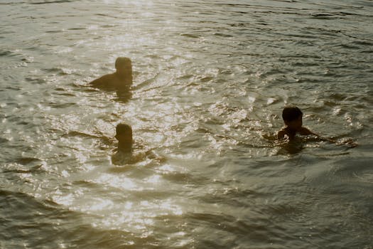 Children swimming in a shimmering lake in Kampot, Cambodia, during sunset. Perfect summer vacation vibe.