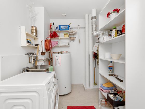 A utility room with a washing machine and a water heater against the wall