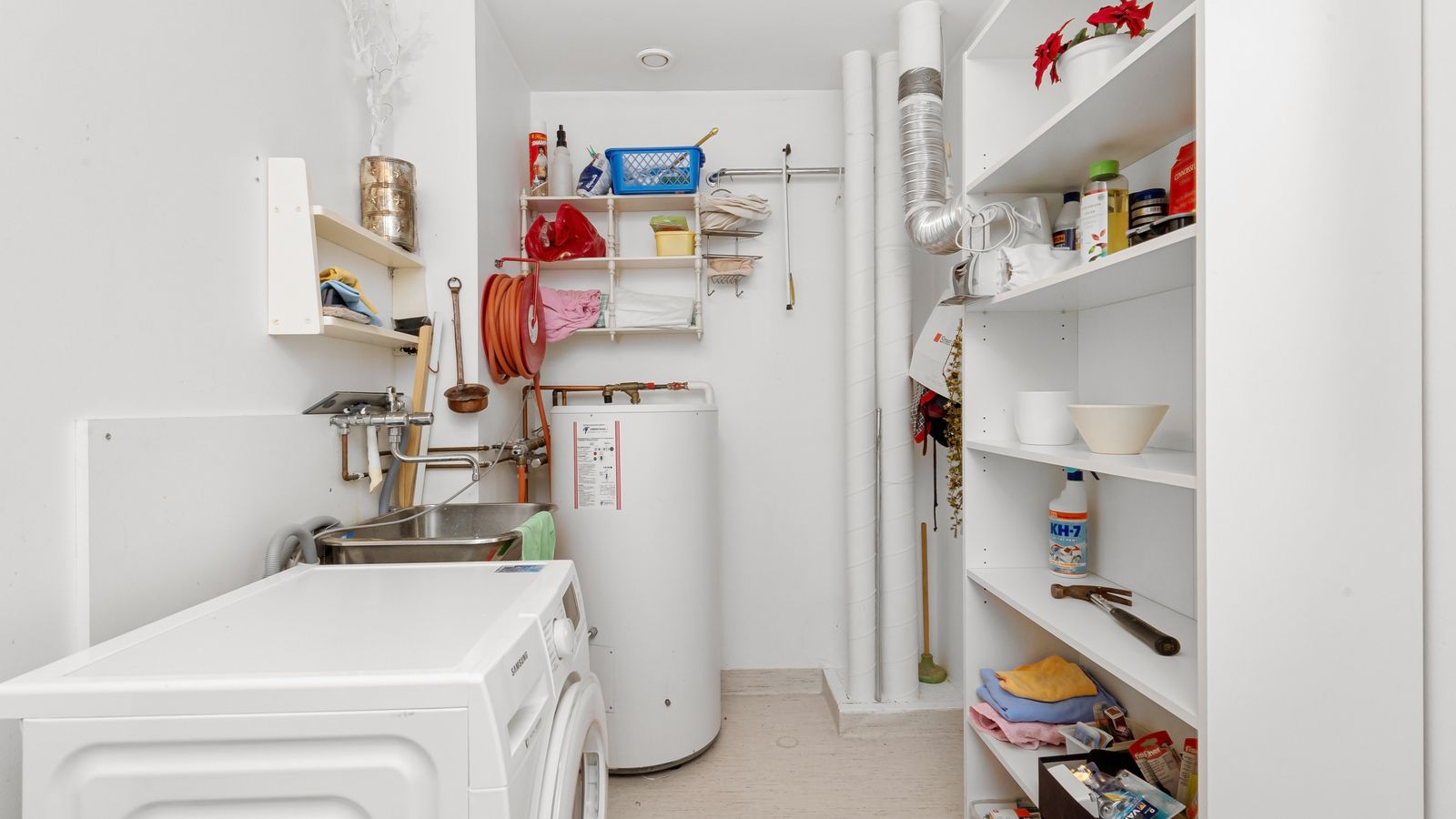 A tank water heater installed in a home laundry and utility room