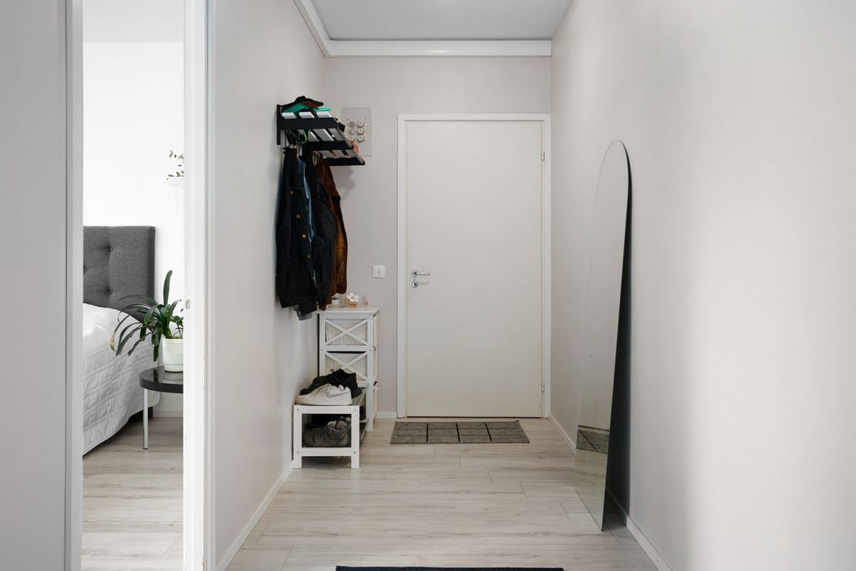 Minimalist white hallway with simple modern furnishings and a tidy boot nook