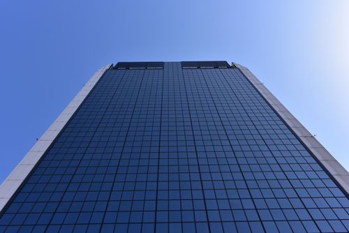 Free Low-angle shot of a tall glass skyscraper against a clear blue sky, showcasing modern architecture. Stock Photo