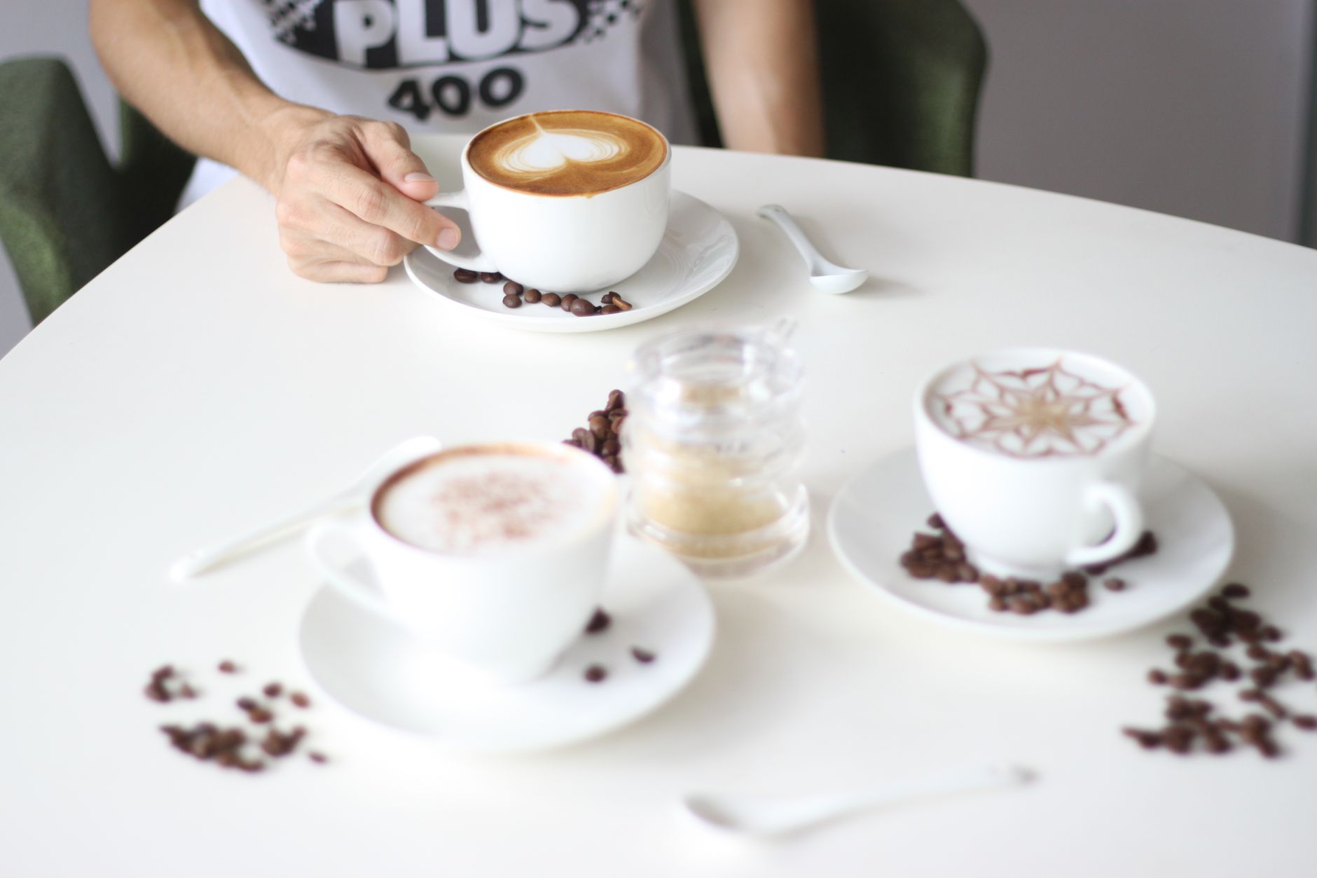 A stylish arrangement of various coffee cups on a café table with a person reaching for one.