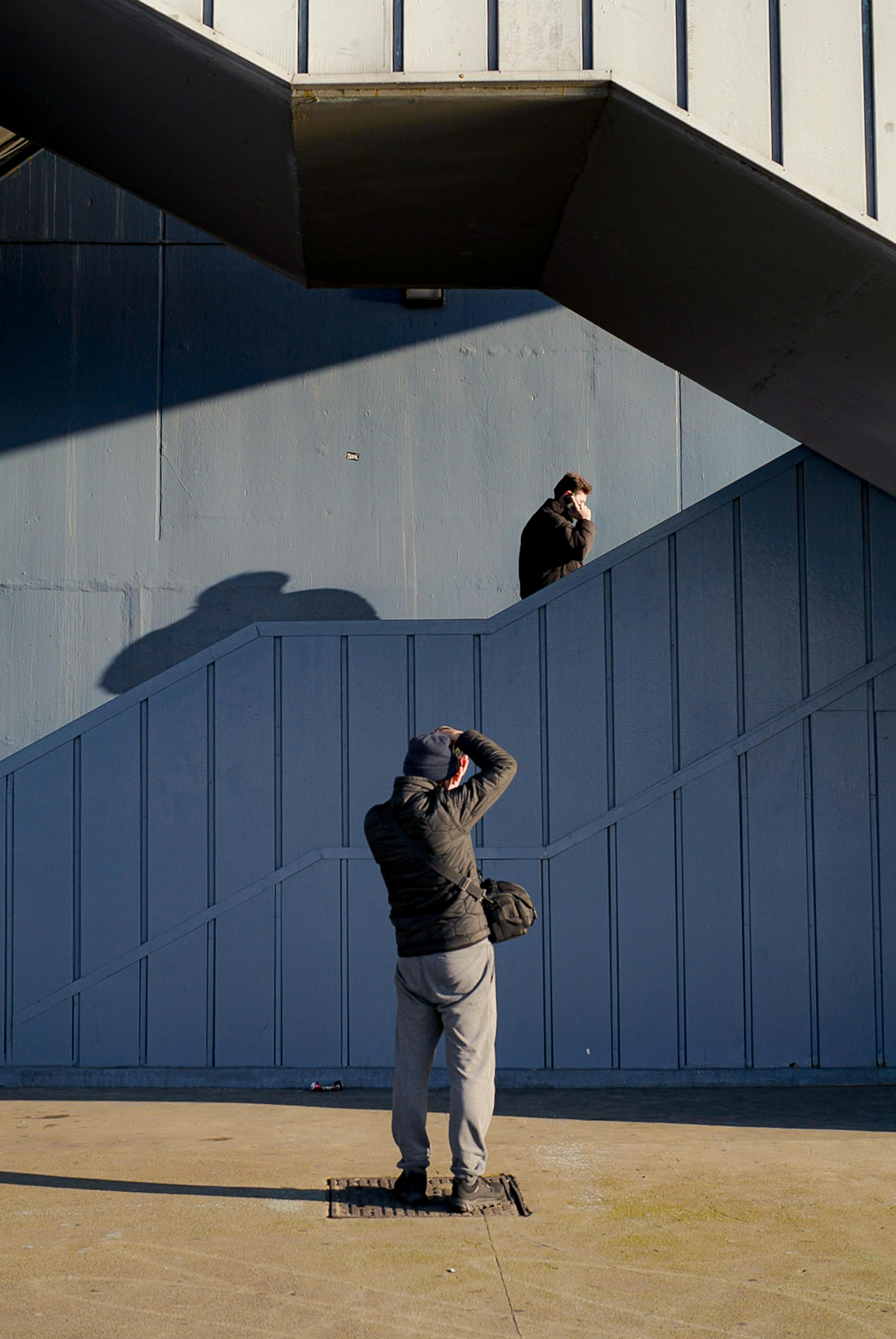 A photographer takes a picture of a man on an urban staircase, capturing city life.