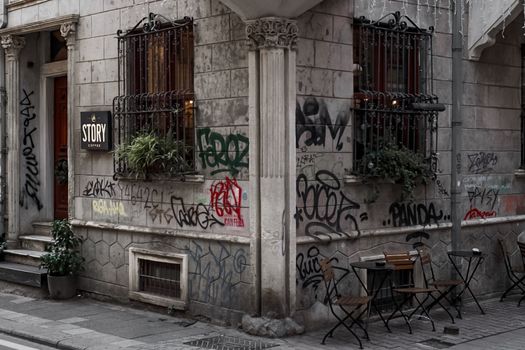 Coffee shop corner with graffiti-covered walls and outdoor seating.