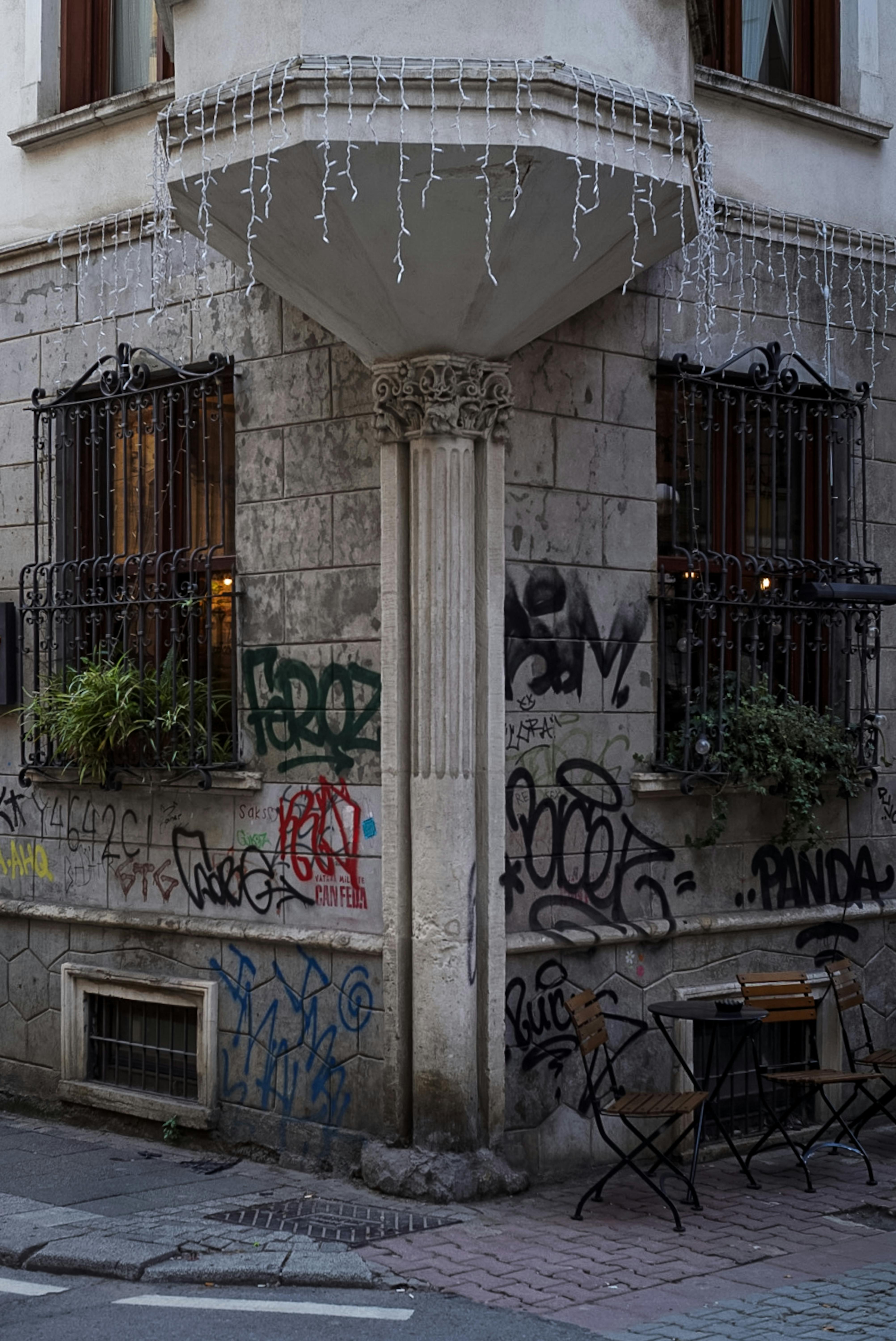 Free A city corner with graffiti-covered walls, a small table, and chairs in an urban setting. Stock Photo
